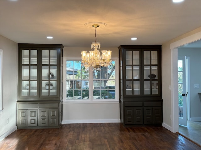 unfurnished dining area with dark hardwood / wood-style flooring and a chandelier