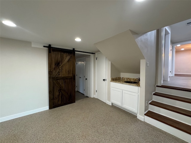 additional living space featuring sink, a barn door, and carpet floors