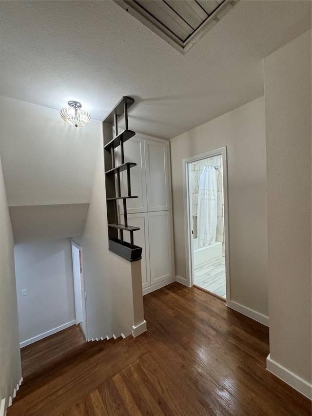 bonus room with dark hardwood / wood-style floors, a textured ceiling, and vaulted ceiling