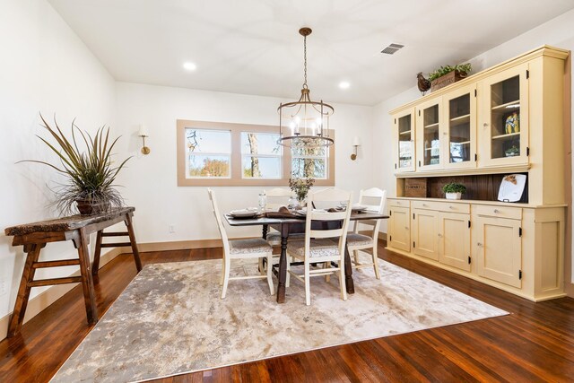 dining space with dark hardwood / wood-style flooring and a chandelier