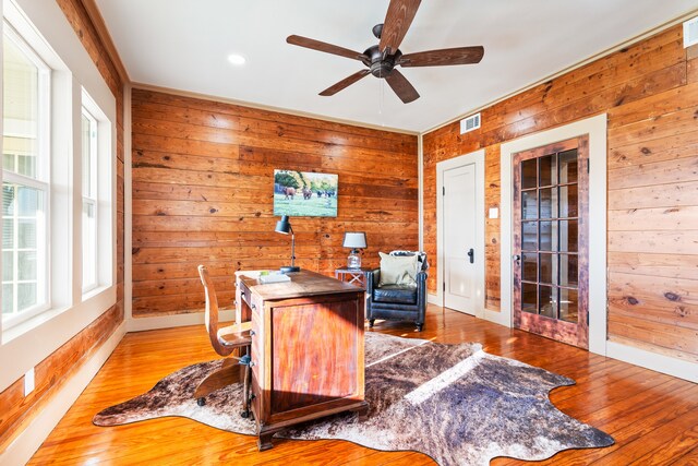 office space with hardwood / wood-style floors, ceiling fan, and wood walls