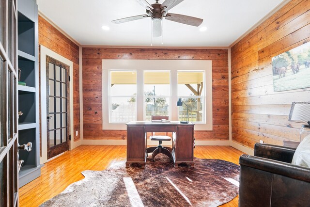 home office featuring wooden walls, french doors, ceiling fan, and light hardwood / wood-style flooring