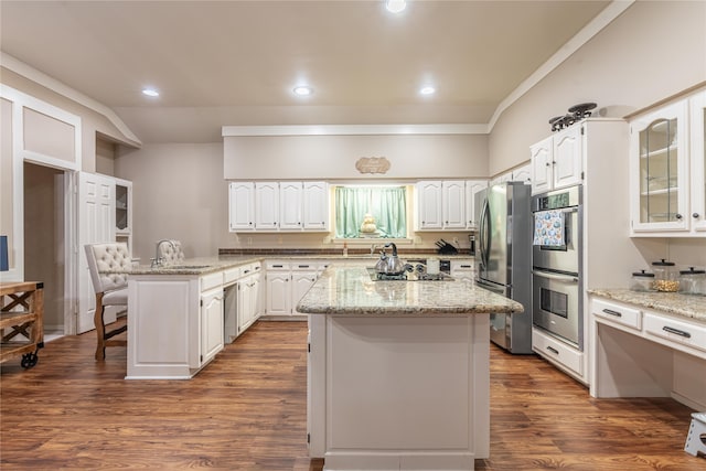 kitchen featuring stainless steel appliances, dark wood-type flooring, a center island, white cabinets, and a breakfast bar area