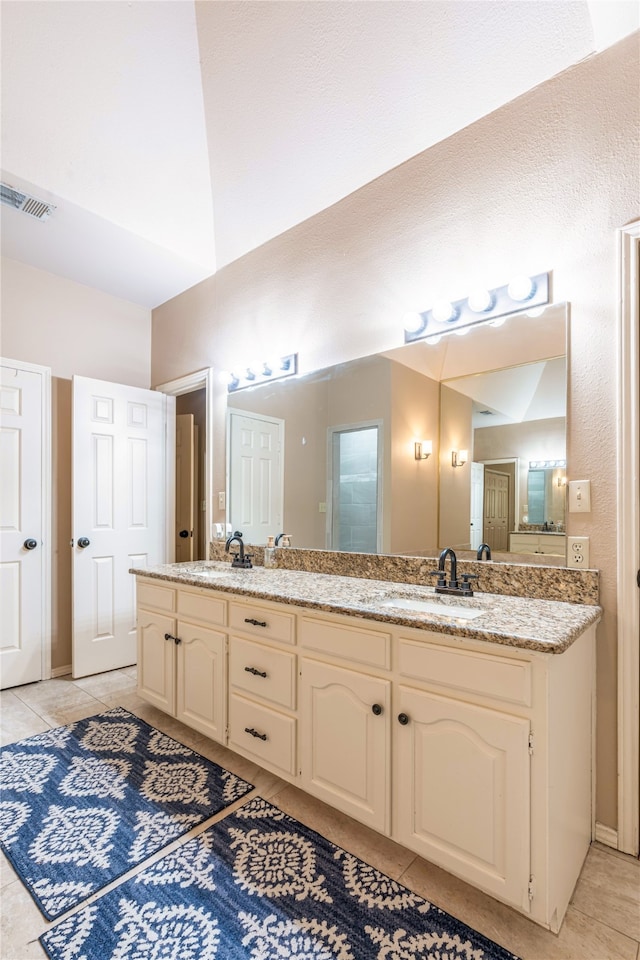 bathroom with vanity, vaulted ceiling, and tile patterned floors