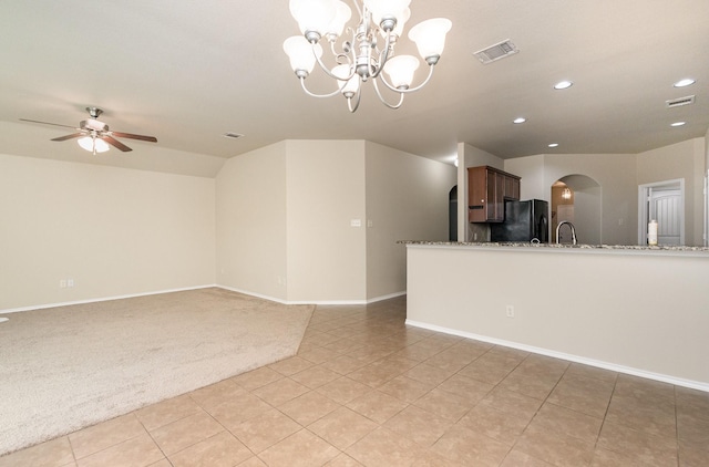 unfurnished living room with sink, light colored carpet, and ceiling fan with notable chandelier