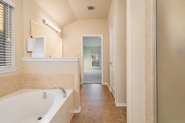 bathroom featuring tile patterned floors, a tub to relax in, and vaulted ceiling