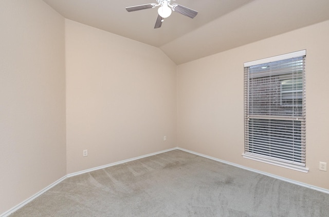 spare room featuring light carpet, vaulted ceiling, and ceiling fan