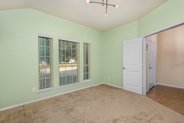 empty room with carpet flooring, vaulted ceiling, and a chandelier