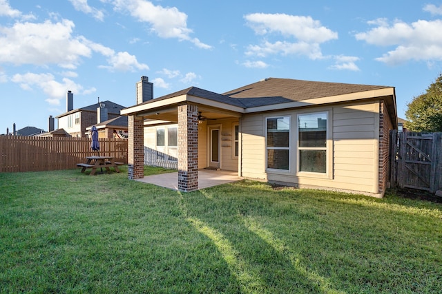 back of house with a yard and a patio