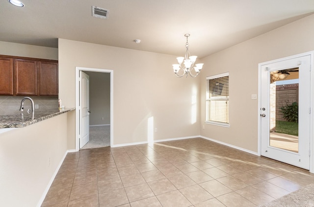 unfurnished dining area with sink, light tile patterned floors, and an inviting chandelier