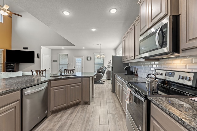 kitchen with a textured ceiling, decorative light fixtures, sink, and stainless steel appliances