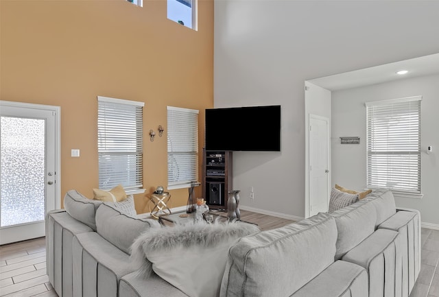 living room featuring light hardwood / wood-style flooring, a healthy amount of sunlight, and a high ceiling