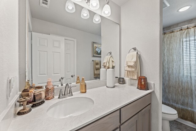 bathroom with walk in shower, vanity, and toilet