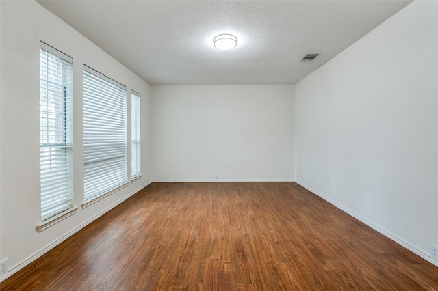 spare room featuring dark hardwood / wood-style floors and a textured ceiling