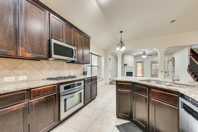 kitchen featuring ceiling fan with notable chandelier, sink, vaulted ceiling, appliances with stainless steel finishes, and dark brown cabinetry