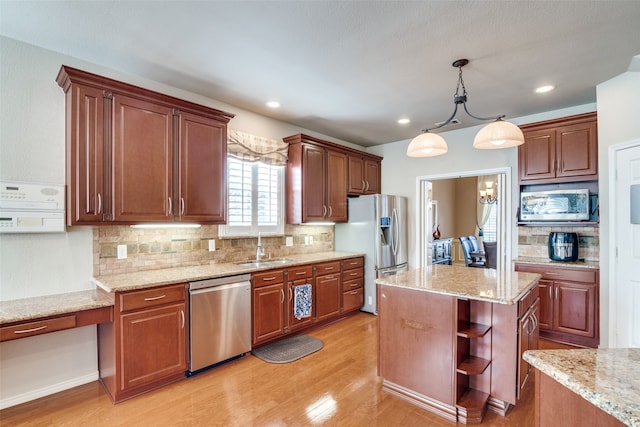 kitchen featuring stainless steel appliances, a center island, hanging light fixtures, sink, and light hardwood / wood-style flooring