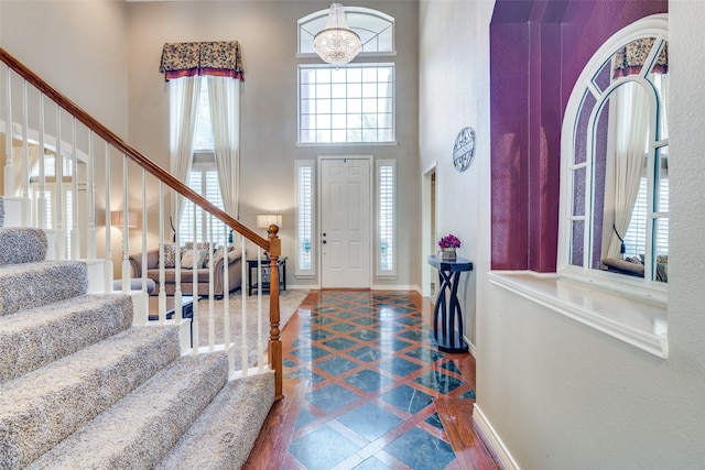 entrance foyer with a towering ceiling, wood-type flooring, and an inviting chandelier