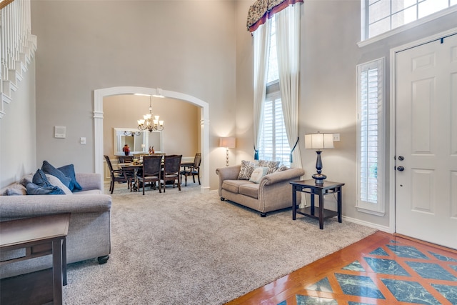 living room featuring a high ceiling, a wealth of natural light, a chandelier, and carpet flooring