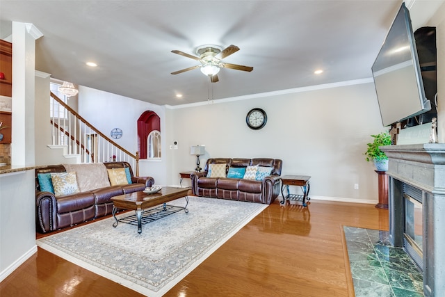 living room featuring hardwood / wood-style floors, a fireplace, ceiling fan, and ornamental molding