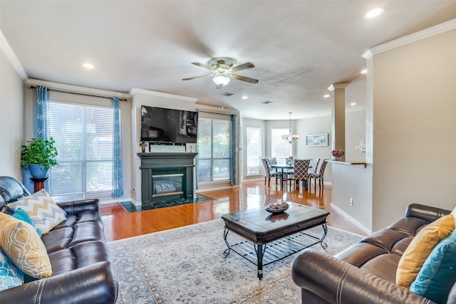 living room featuring a premium fireplace, ceiling fan, light wood-type flooring, and crown molding