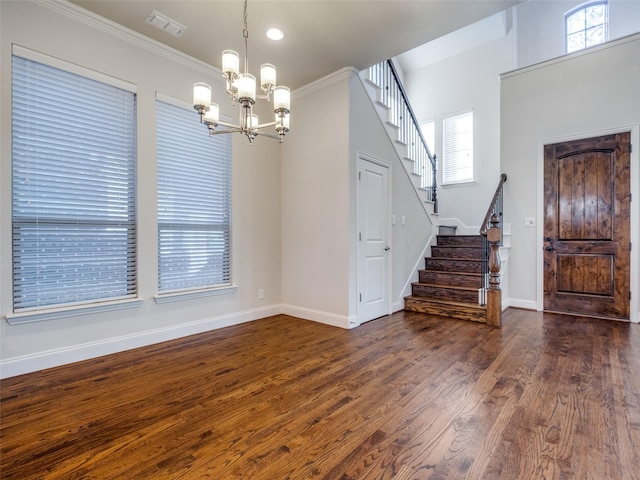 interior space with dark hardwood / wood-style flooring, crown molding, a wealth of natural light, and a chandelier