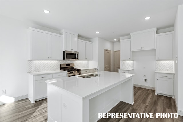 kitchen with wood-type flooring, a center island with sink, stainless steel appliances, white cabinetry, and sink