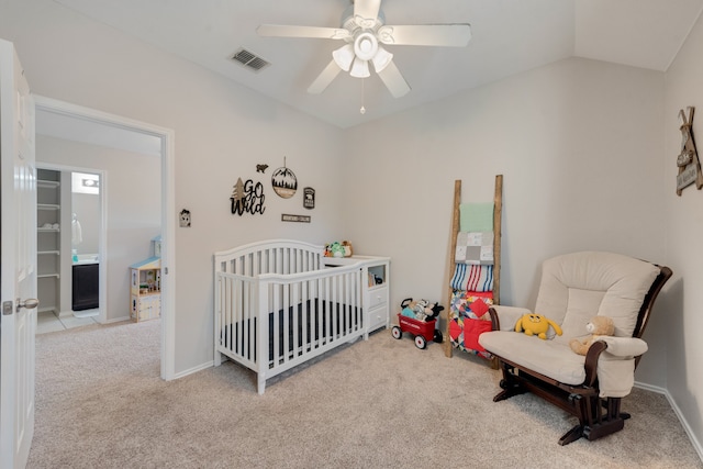 bedroom with a crib, light carpet, vaulted ceiling, and ceiling fan