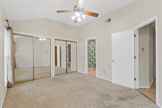 unfurnished bedroom featuring carpet floors, multiple closets, lofted ceiling, and ceiling fan