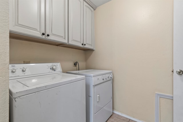 washroom featuring cabinets, washing machine and dryer, and light tile patterned flooring