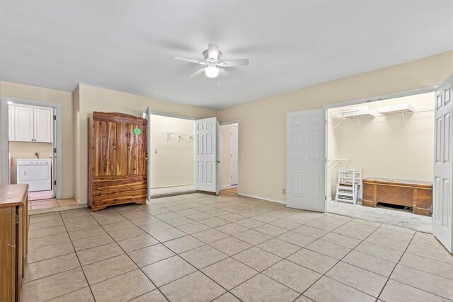 unfurnished bedroom with ceiling fan, light tile patterned floors, washer / dryer, a closet, and an AC wall unit