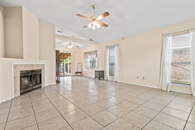 unfurnished living room featuring ceiling fan, a tiled fireplace, light tile patterned floors, and vaulted ceiling