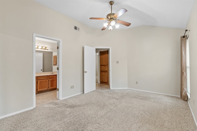 unfurnished bedroom featuring vaulted ceiling, light colored carpet, ceiling fan, and ensuite bath