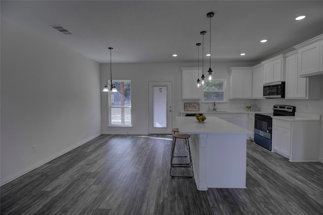 kitchen featuring appliances with stainless steel finishes, sink, white cabinets, hanging light fixtures, and a center island