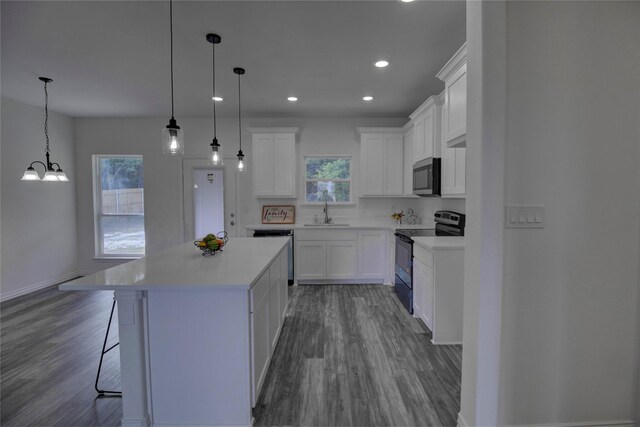 kitchen with range with electric stovetop, white cabinetry, a kitchen island, and decorative light fixtures