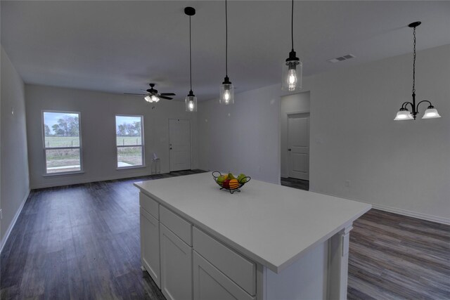 kitchen featuring ceiling fan with notable chandelier, white cabinets, a kitchen island, dark hardwood / wood-style flooring, and decorative light fixtures