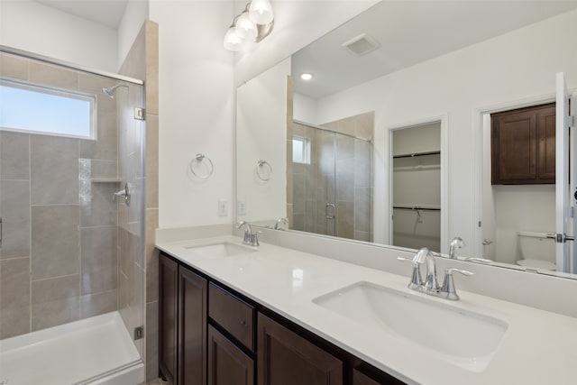 bathroom with a shower with shower door, vanity, and toilet