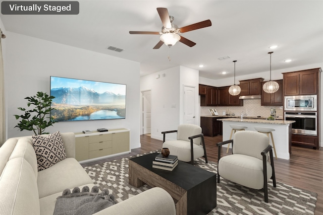 living room featuring ceiling fan and dark hardwood / wood-style flooring