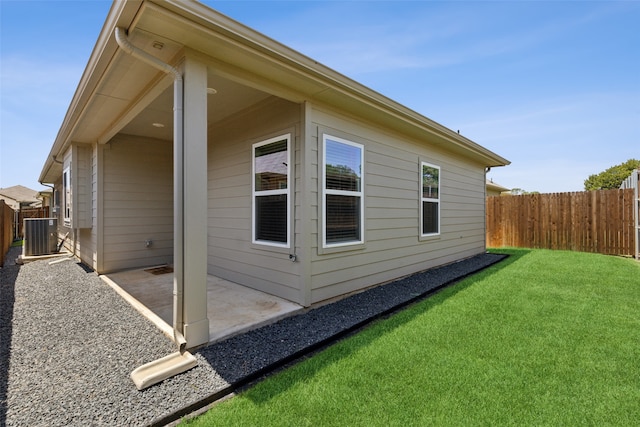 view of side of property featuring a patio, a lawn, and central AC