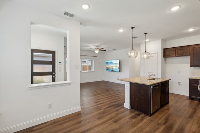 kitchen featuring light stone counters, a center island with sink, dark hardwood / wood-style floors, sink, and dishwasher