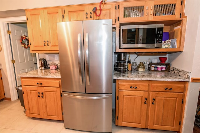 kitchen featuring light tile patterned floors, light stone counters, and stainless steel appliances