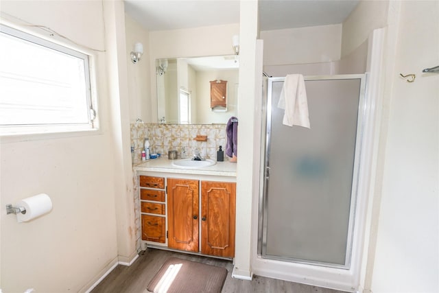 bathroom featuring an enclosed shower, vanity, backsplash, and hardwood / wood-style floors