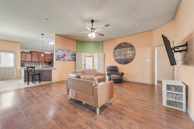 living room with dark wood-type flooring, ceiling fan, and crown molding