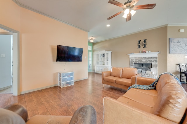 living room featuring a fireplace, ceiling fan, crown molding, and light hardwood / wood-style flooring