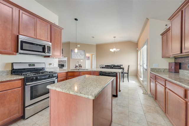 kitchen with stainless steel appliances, sink, ornamental molding, a kitchen island, and decorative light fixtures