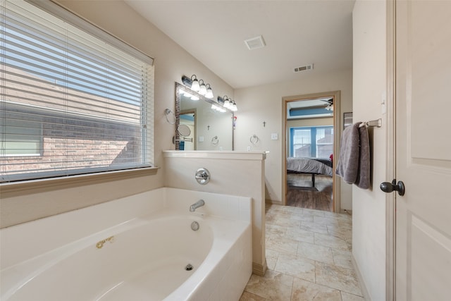 bathroom featuring a wealth of natural light and tiled tub