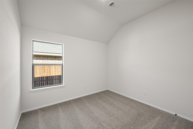 carpeted spare room with vaulted ceiling