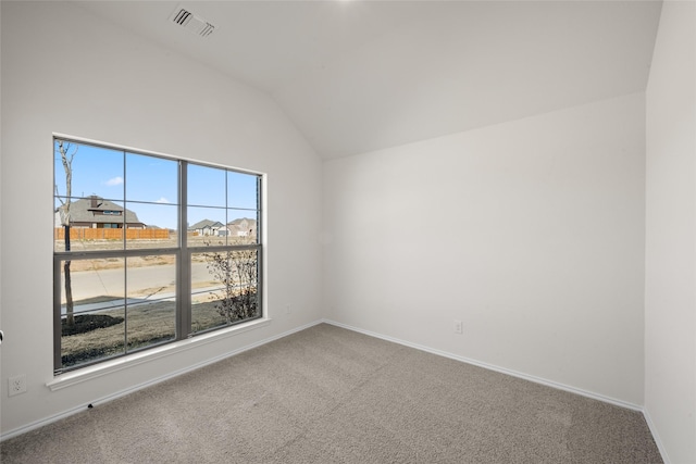 carpeted spare room with a wealth of natural light and vaulted ceiling