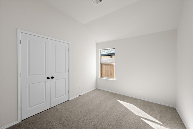 unfurnished bedroom featuring vaulted ceiling, a closet, and carpet flooring