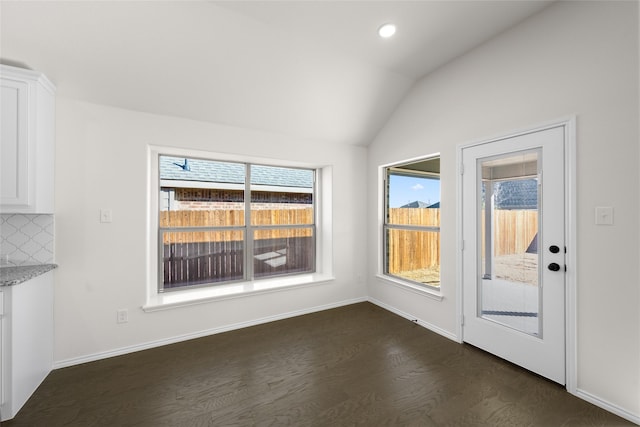 unfurnished dining area featuring plenty of natural light, dark hardwood / wood-style flooring, and vaulted ceiling