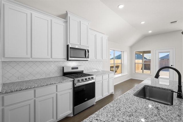 kitchen featuring vaulted ceiling, appliances with stainless steel finishes, sink, and white cabinets